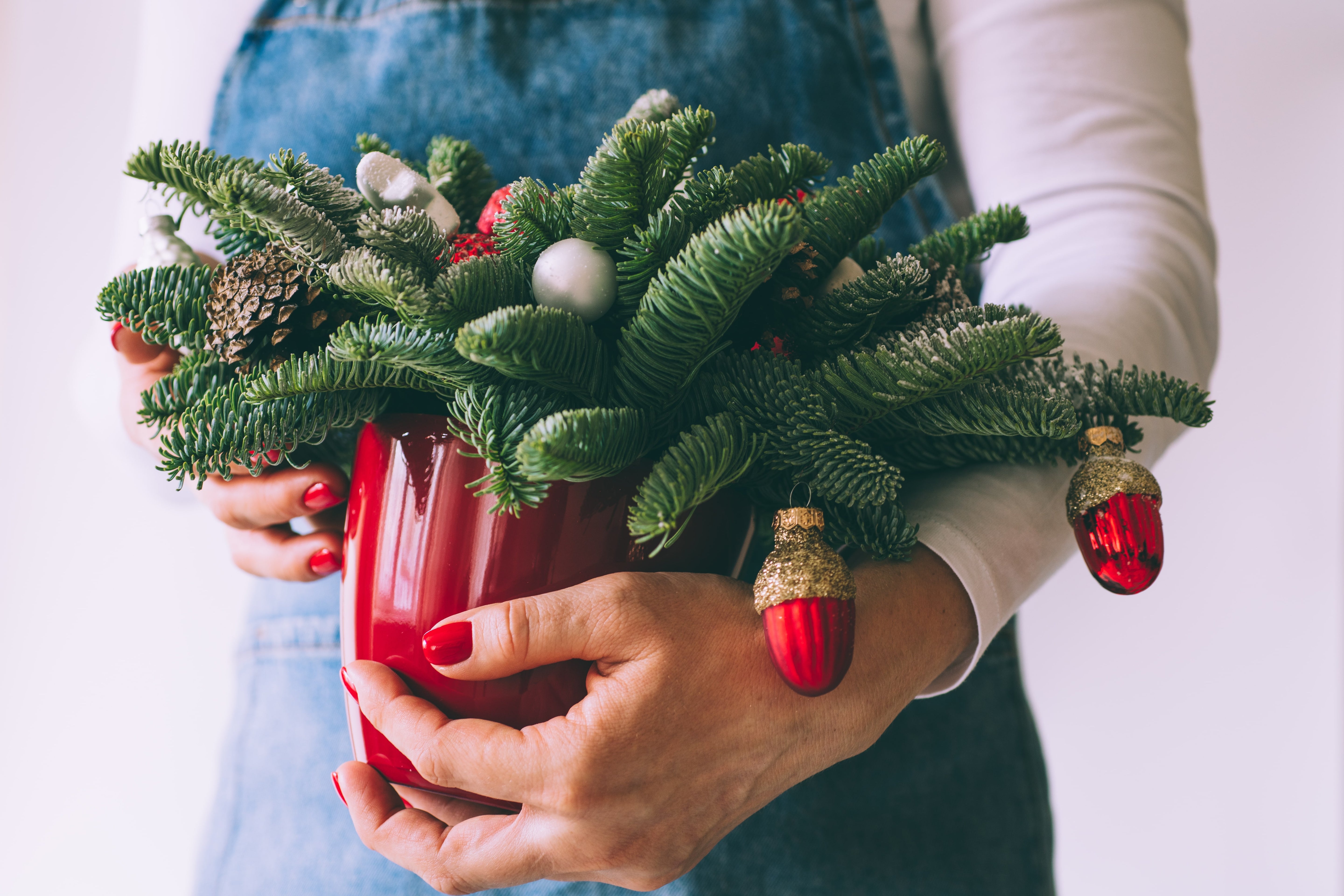 woman holding festive evergreen arrangement.